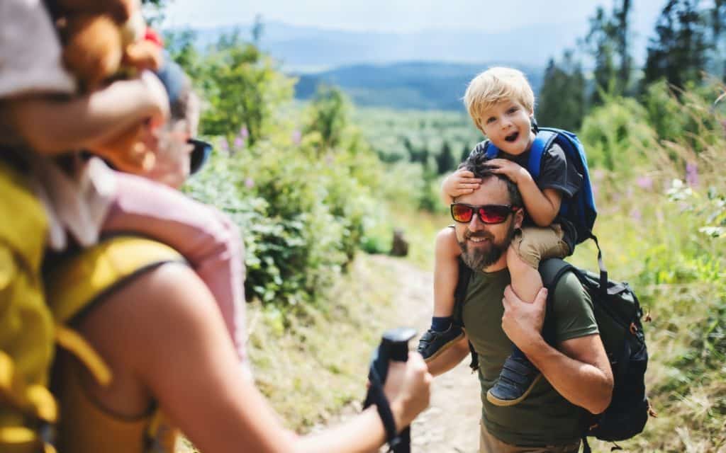Family with small children hiking outdoors in summer nature