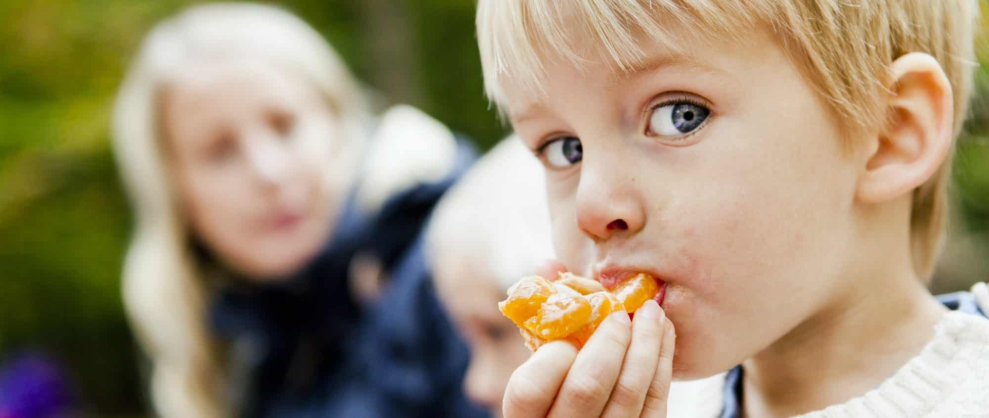 Kleiner Junge isst eine Mandarine